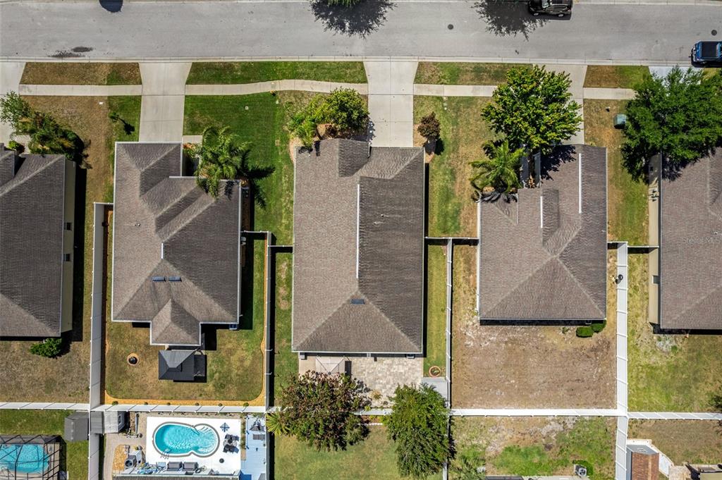 An aerial view shows three suburban houses with shingled roofs, driveways, and fenced backyards — 18334 WAYDALE LOOP, HUDSON, FL