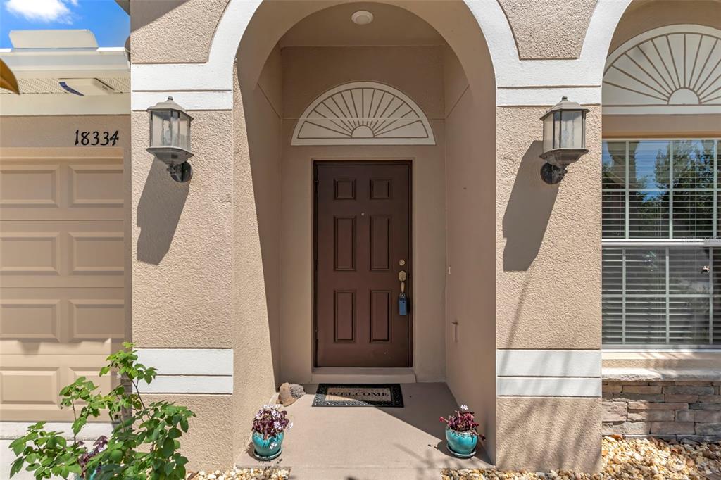 The exterior view shows a brown front door with a transom window and two lanterns — 18334 WAYDALE LOOP, HUDSON, FL