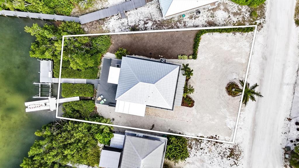 An aerial view shows a house with a metal roof, a dock, and a palm tree — 21 BOCILLA DRIVE, PLACIDA, FL