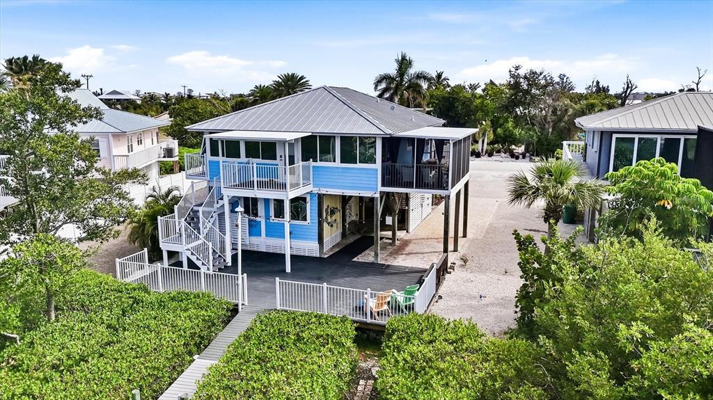 An elevated blue house with a metal roof, wraparound deck, and white railings — 21 BOCILLA DRIVE, PLACIDA, FL