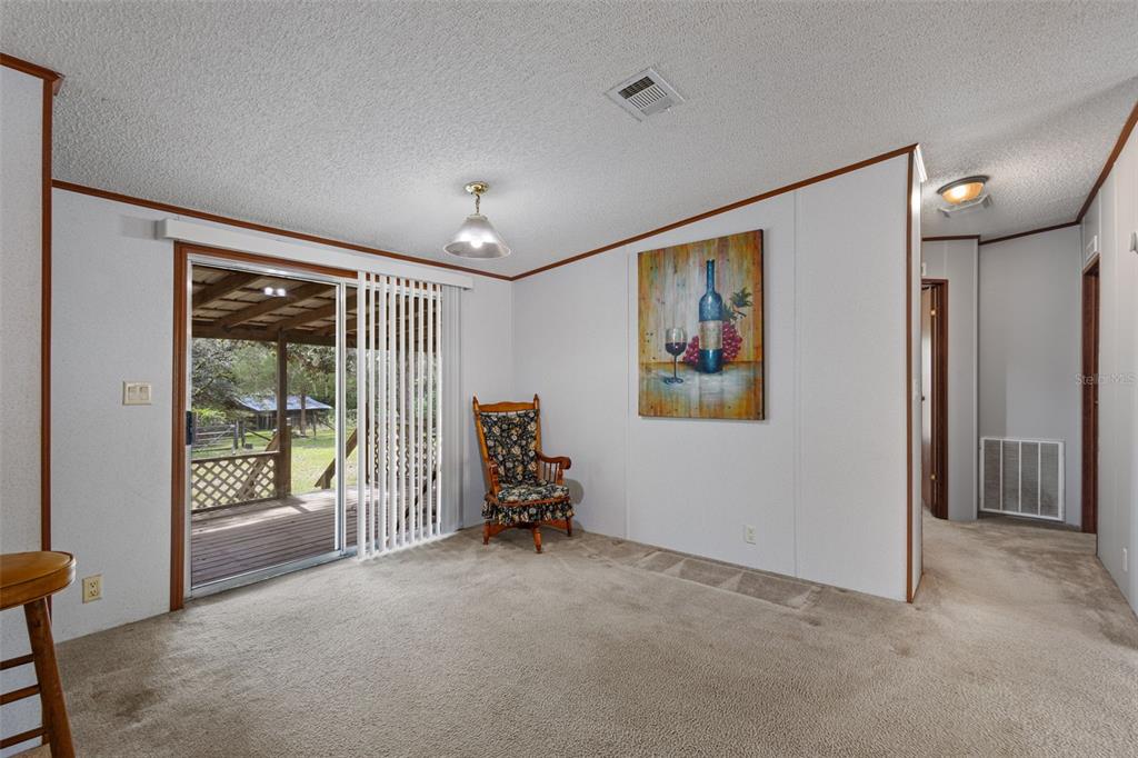 A living room with beige carpet, light gray walls, a ceiling fan, and a front door — 704 SE 791ST STREET, OLD TOWN, FL