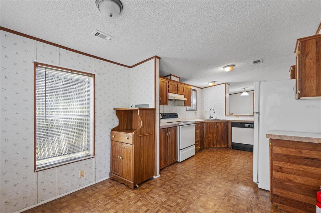 A carpeted living room features white paneled walls, a ceiling fan, and a sliding glass door — 704 SE 791ST STREET, OLD TOWN, FL
