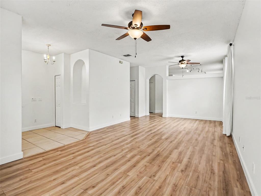 An interior view of a living area with light wood flooring, white walls, and ceiling fans — 14523 KRISTENRIGHT LANE, ORLANDO, FL