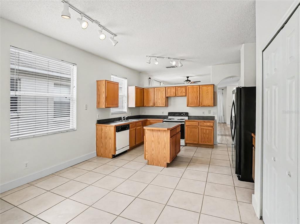 A kitchen features wood cabinets, a central island, tile flooring, and black appliances — 14523 KRISTENRIGHT LANE, ORLANDO, FL