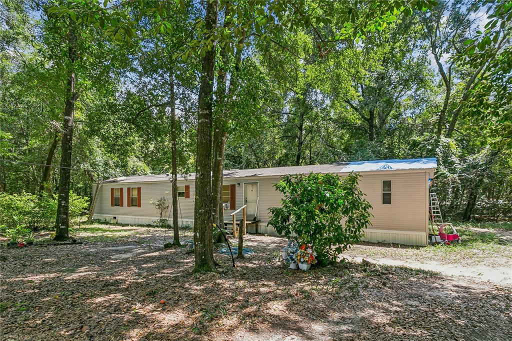 A single-story manufactured home sits in a wooded lot with a light-colored exterior — 2323 CAMORS ROAD, JAY, FL