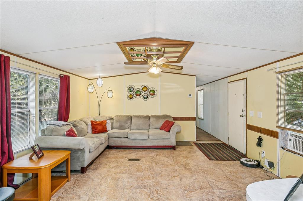 A living room with light yellow walls, a sectional sofa, tile flooring, and a ceiling fan — 2323 CAMORS ROAD, JAY, FL
