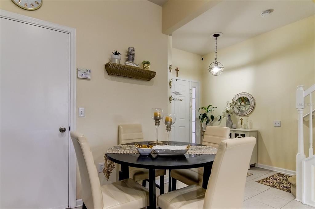A dining area features a round black table with four cream chairs and wall decor — 26642 CASTLEVIEW WAY, WESLEY CHAPEL, FL