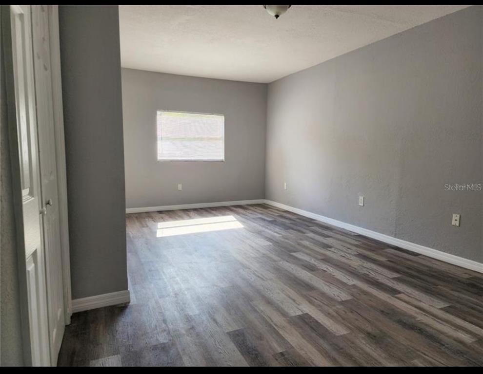 An empty room with gray walls, white trim, and wood-look laminate flooring — 1019 SANTA BARBARA ROAD, ORLANDO, FL