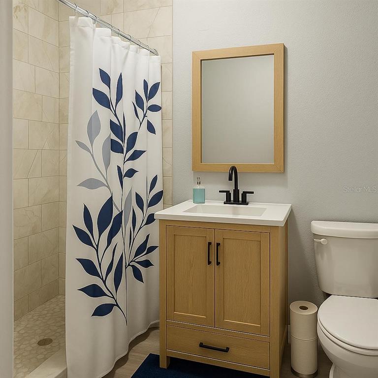 A small bathroom features a light wood vanity, a shower with a leaf-patterned curtain, and toilet — 1019 SANTA BARBARA ROAD, ORLANDO, FL