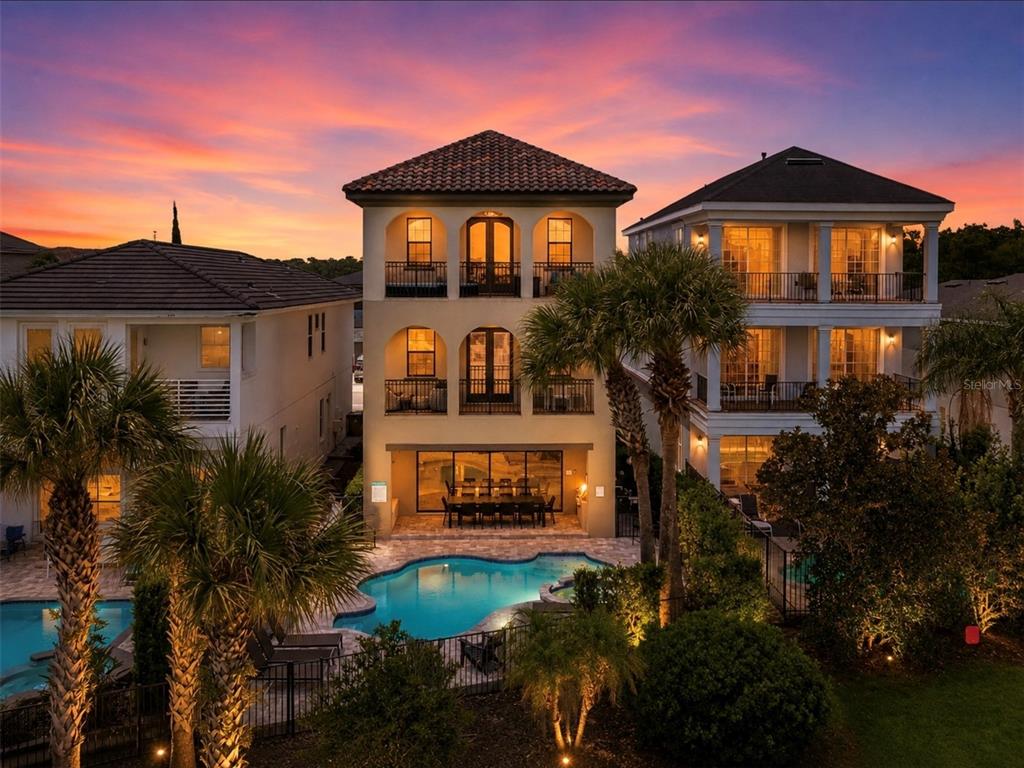 A three-story house with balconies and a swimming pool at sunset — 969 DESERT MOUNTAIN COURT, KISSIMMEE, FL