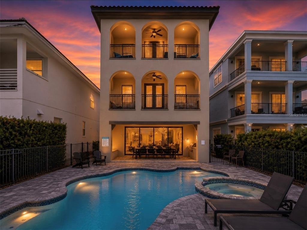 A three-story house with arched balconies and a swimming pool at sunset — 969 DESERT MOUNTAIN COURT, KISSIMMEE, FL