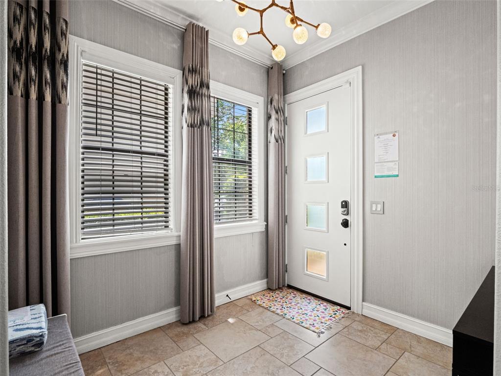 An entryway features gray wallpaper, tile flooring, a white front door, and a modern light fixture — 969 DESERT MOUNTAIN COURT, KISSIMMEE, FL