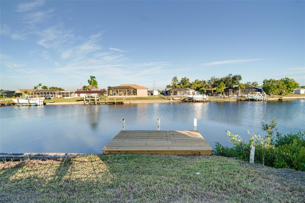 A bright, open-concept room features white marble-look tile floors, a ceiling fan, and a kitchen — 217 W TARPON BOULEVARD NW, PORT CHARLOTTE, FL