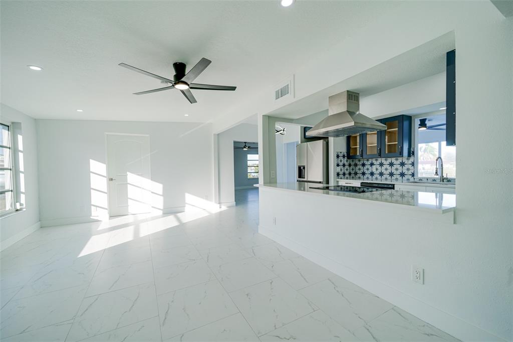 A bright, open-concept kitchen and living area with white tile floors and dark blue cabinetry — 217 W TARPON BOULEVARD NW, PORT CHARLOTTE, FL