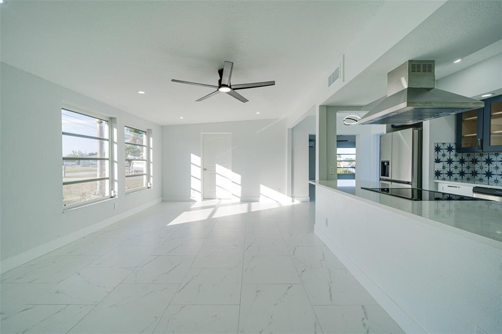 A bright, open-concept kitchen features white marble-look tile floors, navy blue cabinets, and a vent hood — 217 W TARPON BOULEVARD NW, PORT CHARLOTTE, FL