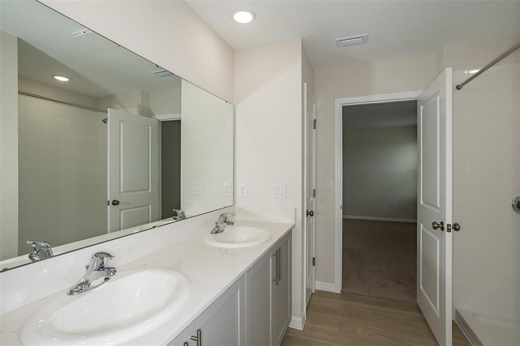 A bathroom features a double vanity with gray cabinets, white countertops, and a large mirror — 34634 SILENT PINE RUN, DADE CITY, FL