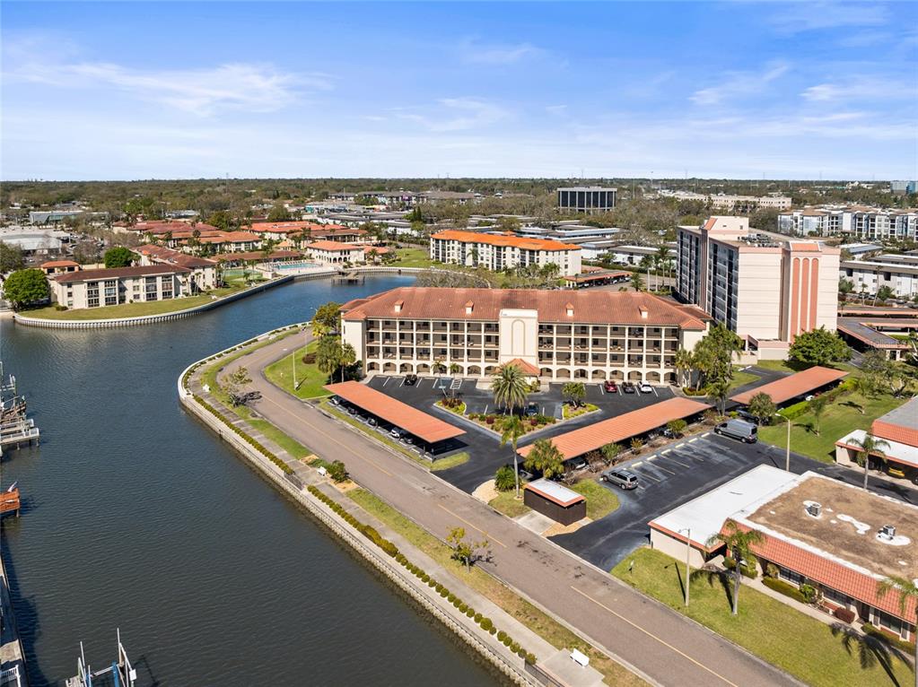 An aerial view shows a multi-story apartment building with covered parking next to a canal — 19029 US HIGHWAY 19 N UNIT 7-9, CLEARWATER, FL