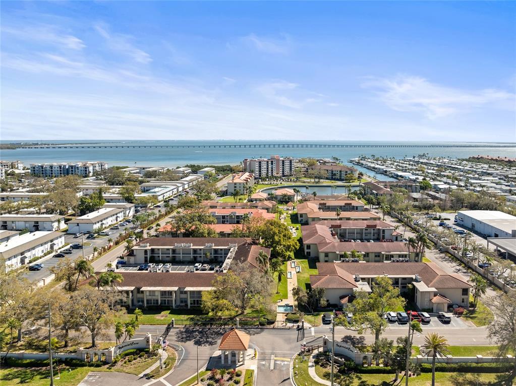 An aerial view shows a multi-building apartment complex with a pool near a large bay — 19029 US HIGHWAY 19 N UNIT 7-9, CLEARWATER, FL