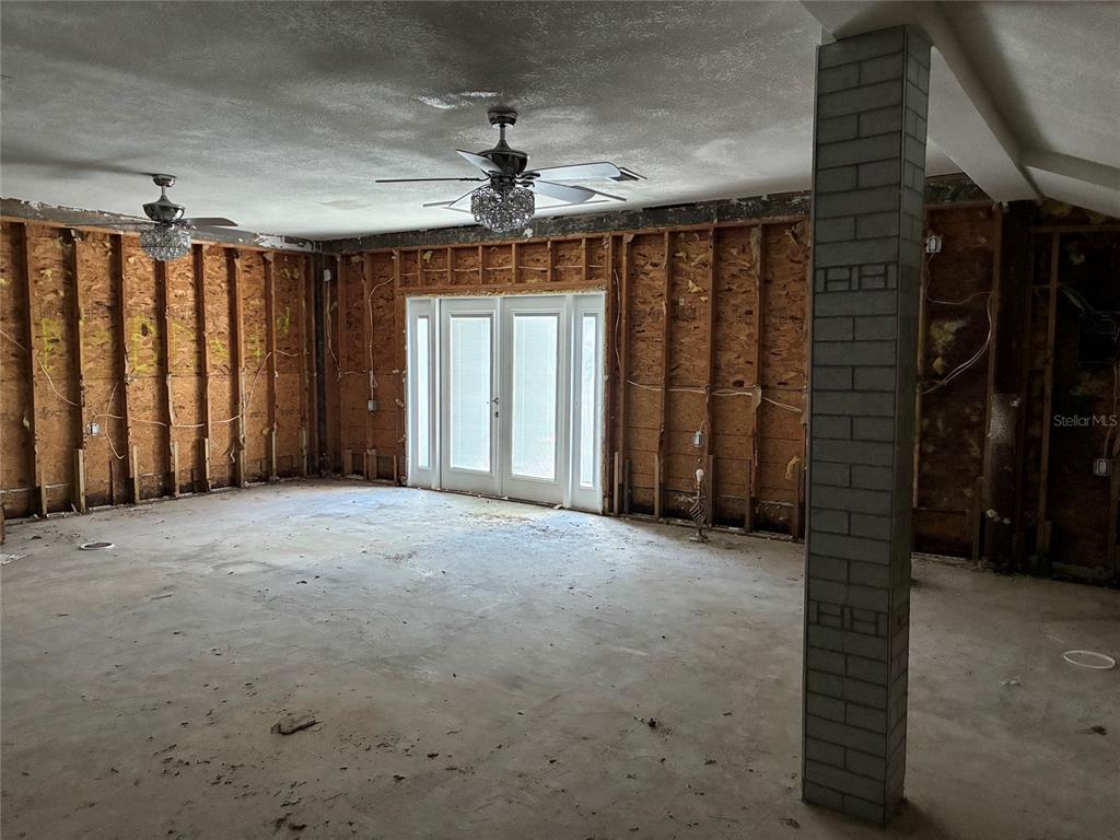 An unfinished room features exposed wall studs, concrete flooring, and two ceiling fans — 9307 RIVER COVE DRIVE, RIVERVIEW, FL