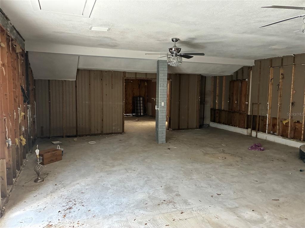 An unfinished room with exposed wall studs, concrete flooring, and a central support pillar — 9307 RIVER COVE DRIVE, RIVERVIEW, FL