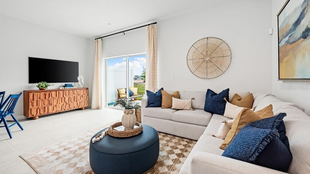 A living room features a sectional sofa, a round blue ottoman, and a wooden media console — 13203 STABLE PLACE, PARRISH, FL