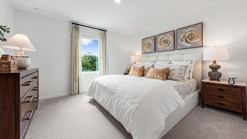 A bedroom features a white bed, two wooden nightstands, a dresser, and three floral wall paintings — 13203 STABLE PLACE, PARRISH, FL