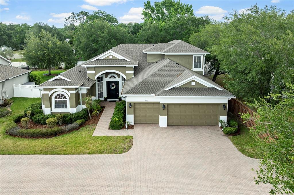A one-story house with a tan stucco exterior, arched windows, and a three-car garage — 925 BAINBRIDGE LOOP, WINTER GARDEN, FL