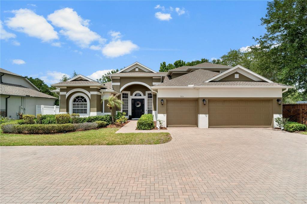 A single-story house with a tan exterior, arched window, and a paved driveway — 925 BAINBRIDGE LOOP, WINTER GARDEN, FL