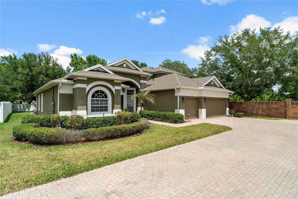 A two-story house with a three-car garage and a paved driveway under a blue sky — 925 BAINBRIDGE LOOP, WINTER GARDEN, FL