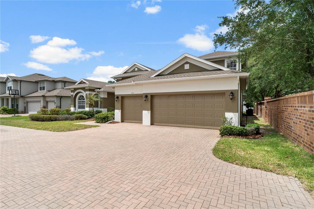 A paved walkway leads to the front entrance of a house with tan stucco walls — 925 BAINBRIDGE LOOP, WINTER GARDEN, FL
