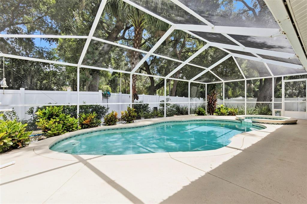 A screened-in swimming pool and hot tub sit on a concrete patio in a backyard — 5016 RIVER LAKE ROAD, WINTER HAVEN, FL