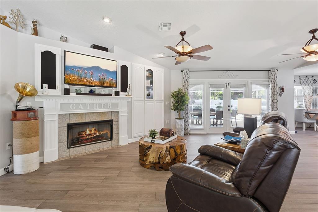 A living room features a fireplace with a television above, wood-look flooring, and leather seating — 5016 RIVER LAKE ROAD, WINTER HAVEN, FL