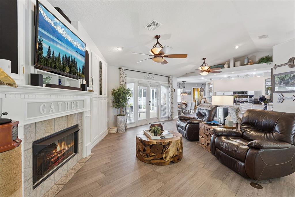 A living room features a stone fireplace, wood-look flooring, and two brown leather armchairs — 5016 RIVER LAKE ROAD, WINTER HAVEN, FL
