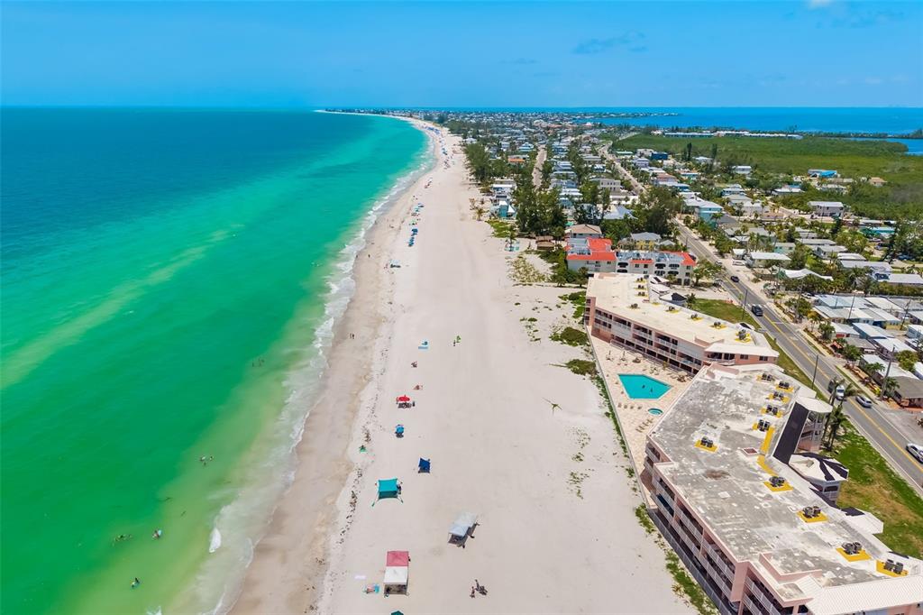 An aerial view of a sandy beach coastline with a multi-story resort and swimming pool — 2513 AVENUE B UNIT B, BRADENTON BEACH, FL