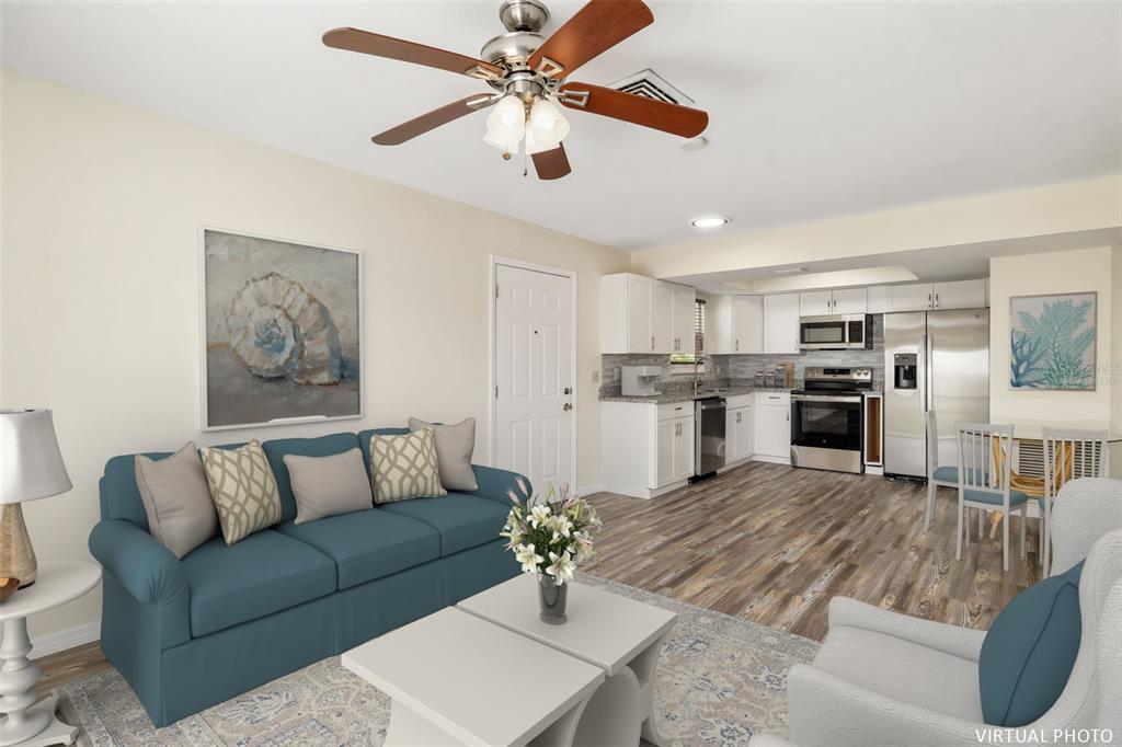 This virtual photo shows an open-concept living room and kitchen with wood-look flooring — 2513 AVENUE B UNIT B, BRADENTON BEACH, FL