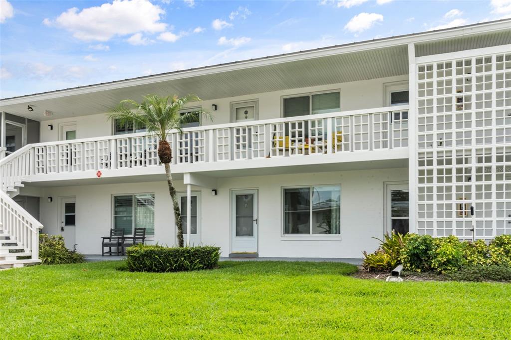 A two-story white apartment building features exterior walkways, a palm tree, and a grassy lawn — 1140 S ORLANDO AVENUE UNIT G3, MAITLAND, FL