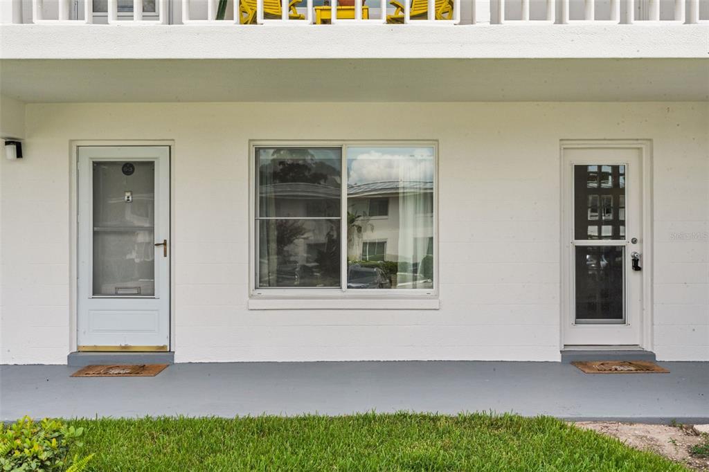 A white exterior wall features two doors flanking a large sliding window above a walkway — 1140 S ORLANDO AVENUE UNIT G3, MAITLAND, FL