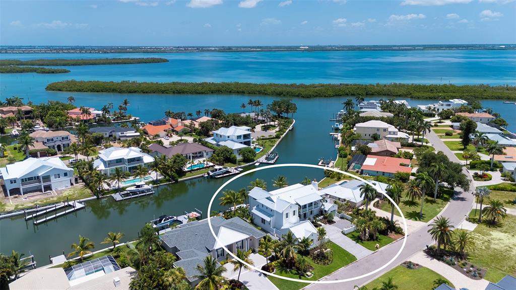 An aerial view shows a white multi-story house with a pool along a canal — 711 OLD COMPASS ROAD, LONGBOAT KEY, FL