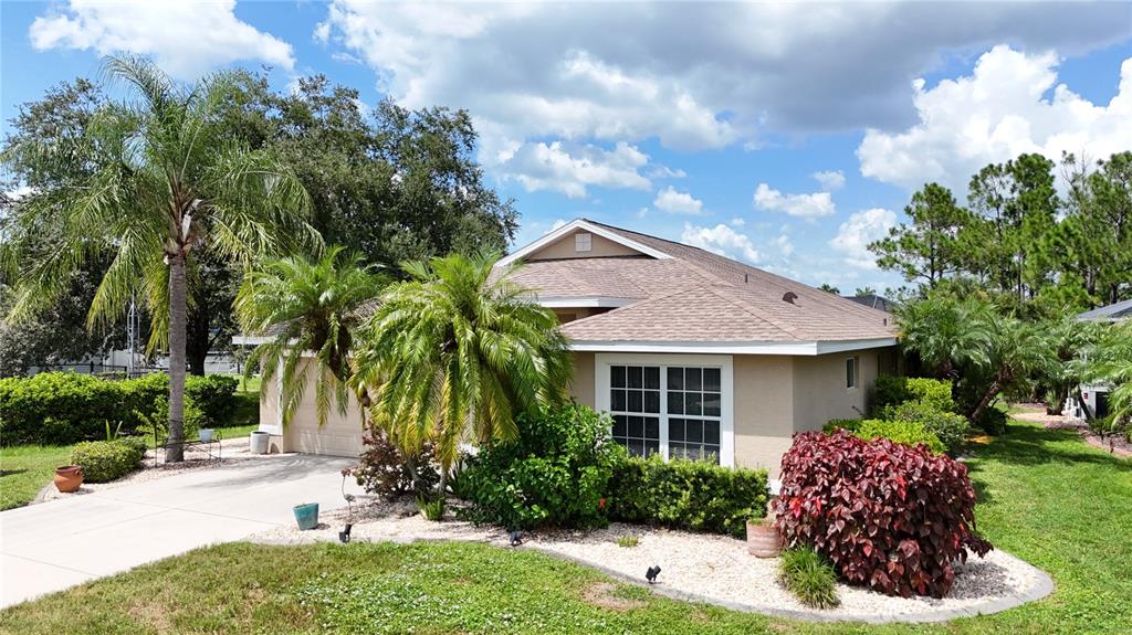 A tan single-story house features a palm-lined driveway and a landscaped front yard — 1520 SCARLETT AVENUE, NORTH PORT, FL