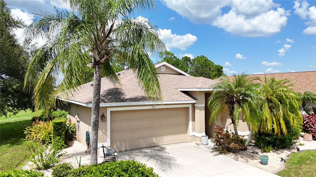 A single-story house with a beige garage, a palm tree, and a light-colored driveway — 1520 SCARLETT AVENUE, NORTH PORT, FL