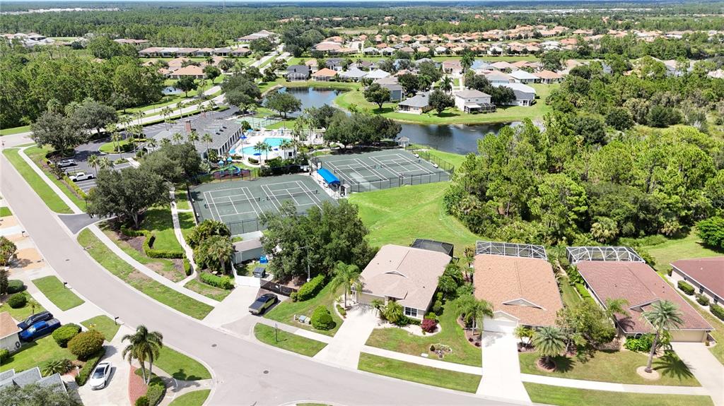 An aerial view shows a residential neighborhood with tennis courts, a pool, and nearby houses — 1520 SCARLETT AVENUE, NORTH PORT, FL
