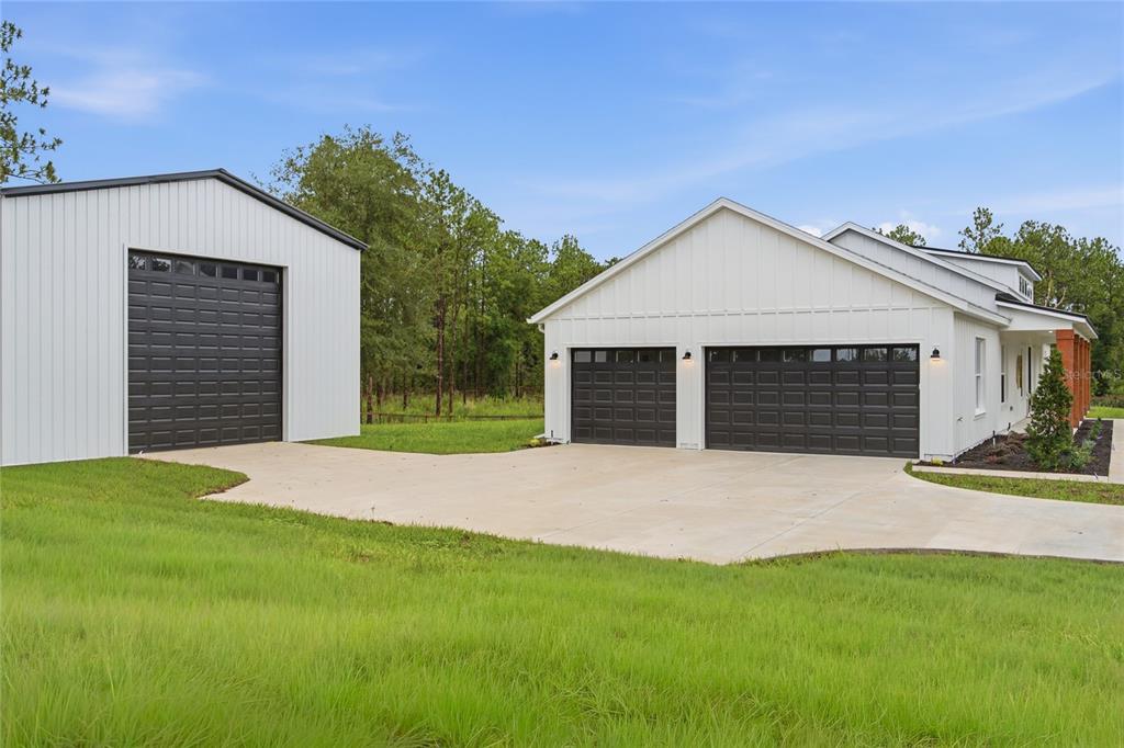 A white house with a two-car garage and a separate detached metal garage building — 7539 SW 129TH TERRACE ROAD, DUNNELLON, FL