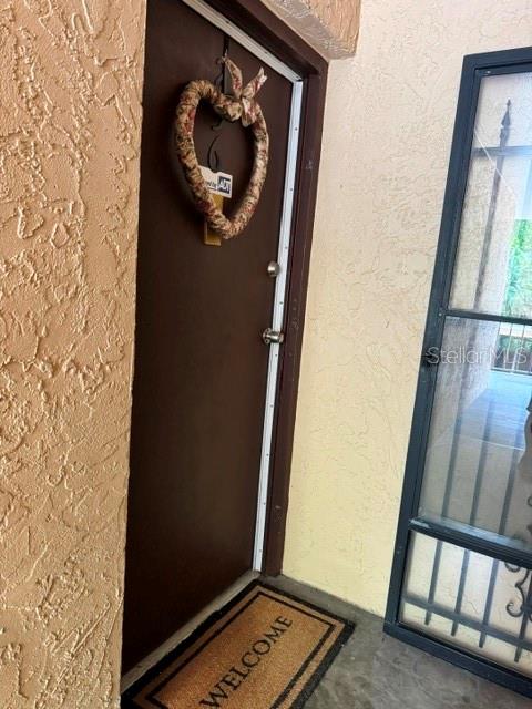 A brown front door with a heart-shaped wreath and a welcome mat on a porch — 5820 N CHURCH AVENUE UNIT 256, TAMPA, FL