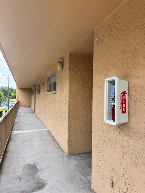 An exterior walkway of a multi-story building features a wall-mounted fire extinguisher cabinet — 5820 N CHURCH AVENUE UNIT 256, TAMPA, FL