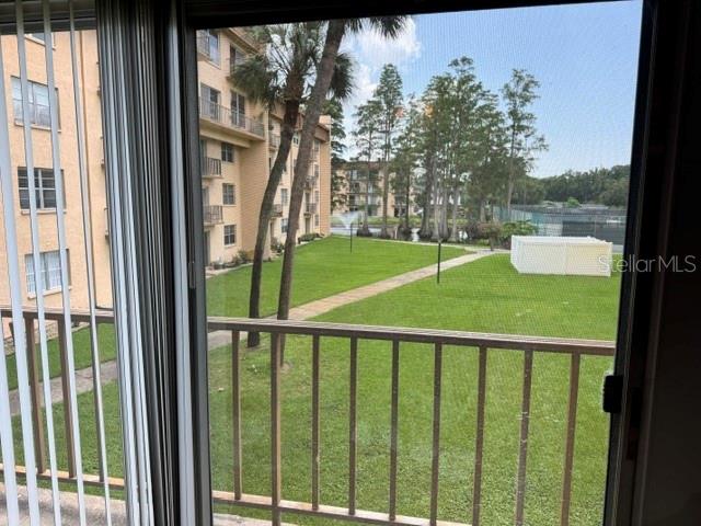 A view from a balcony overlooking a grassy courtyard, palm trees, and a neighboring building — 5820 N CHURCH AVENUE UNIT 256, TAMPA, FL