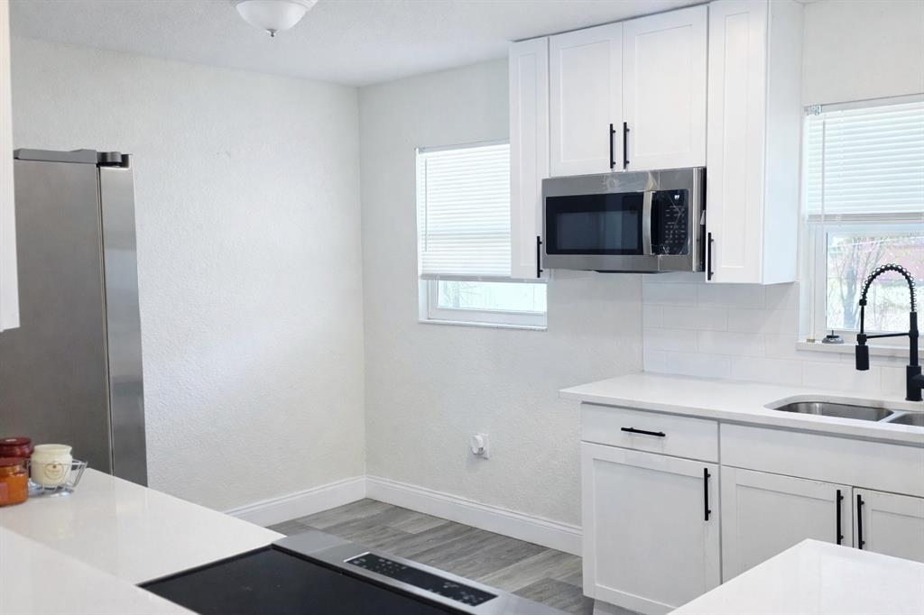 A modern kitchen features white cabinets, stainless steel appliances, and a white countertop — 713 THOMAS AVENUE, COCOA, FL