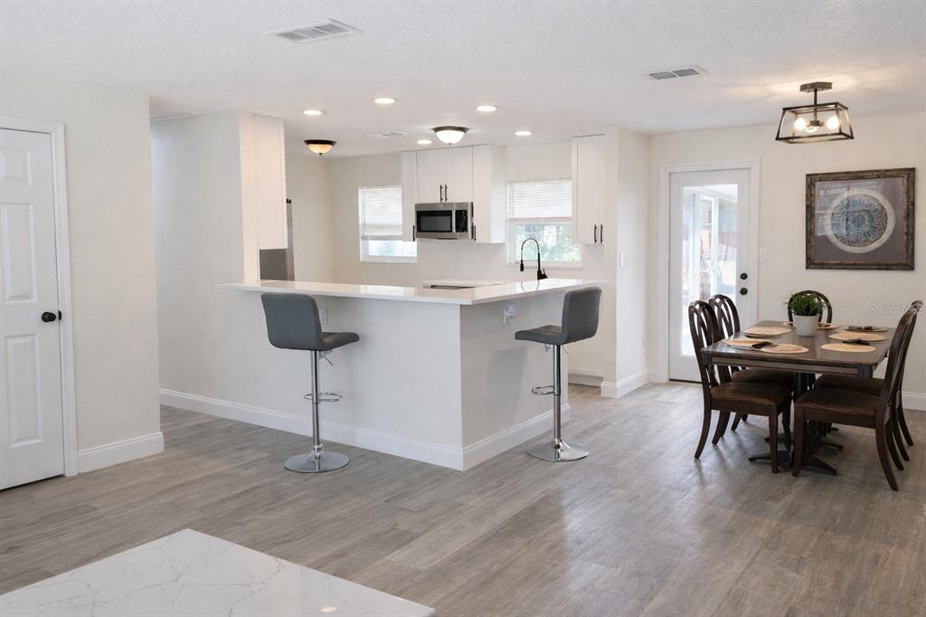 A kitchen with white cabinets, a breakfast bar, and a dining area with wood flooring — 713 THOMAS AVENUE, COCOA, FL