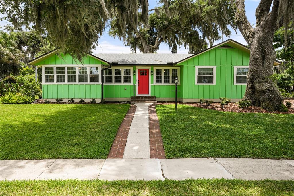 A bright green single-story house with a red front door and a brick walkway — 1338 HEIM ROAD, MOUNT DORA, FL
