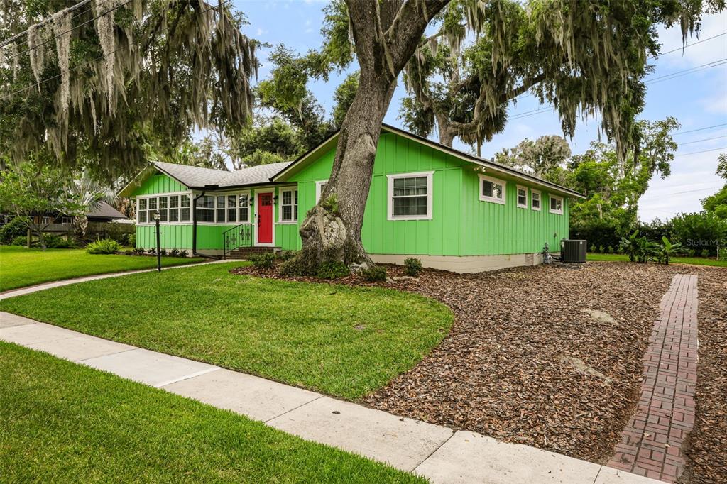A bright green single-story house with a red door and a large tree in front — 1338 HEIM ROAD, MOUNT DORA, FL