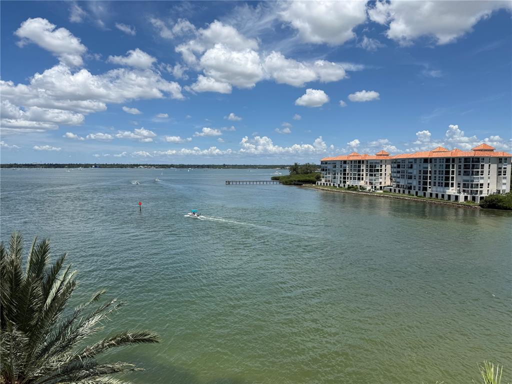 An aerial view shows a multi-story waterfront condominium building next to a bridge and road — 4993 BACOPA LANE S UNIT 505, ST PETERSBURG, FL